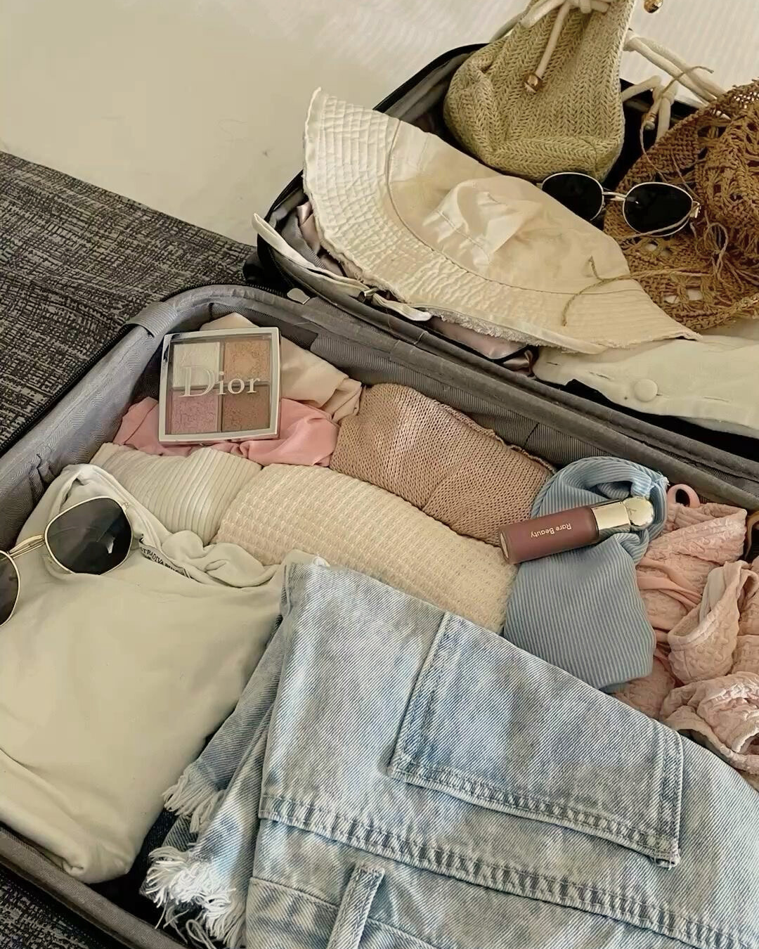 Mala de viagem organizada com roupas e acessórios neutros