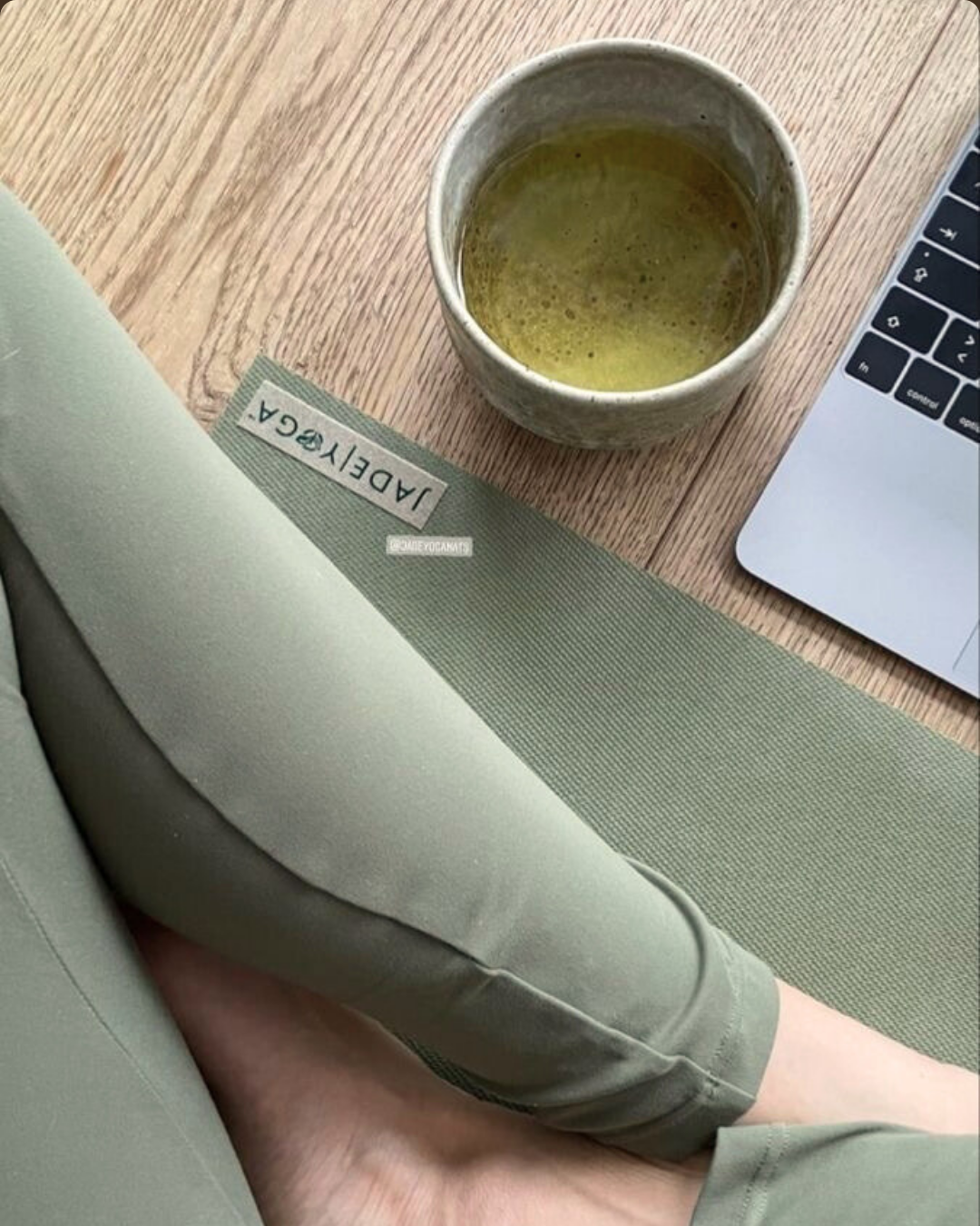 Tapete de yoga verde e xícara de chá ao lado de notebook